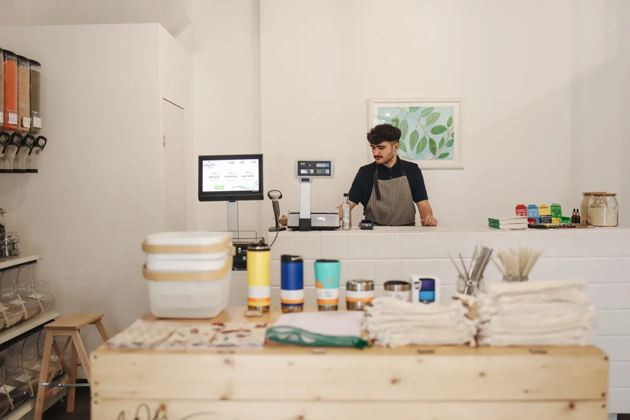 Commerçant souriant derrière le comptoir de sa boutique, prêt à accueillir ses clients.