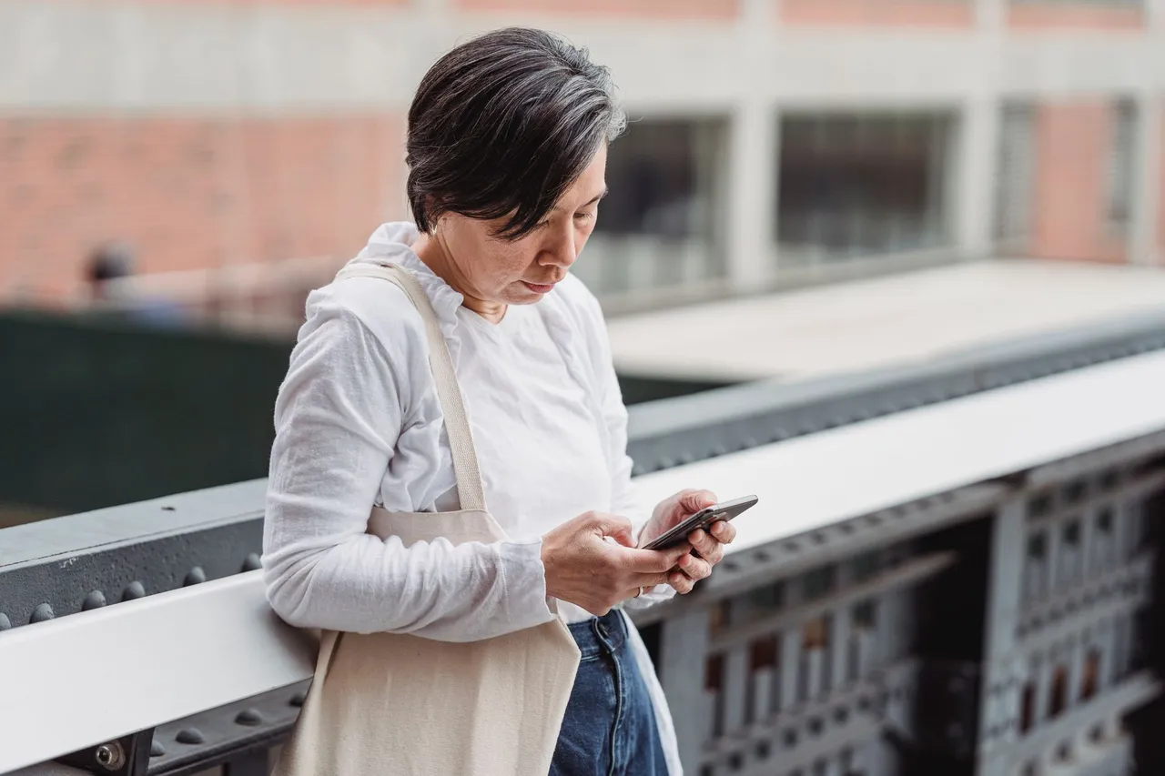 Cliente consultant son smartphone dans la rue pour trouver un commerce ou un artisan de proximité.